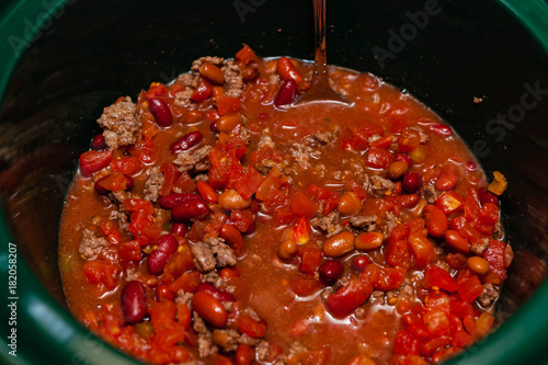 mixing the ingredents for chili in a crock pot