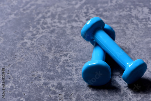 Barbells placed crosswise in closeup. Dumbbells made of cyan plastic