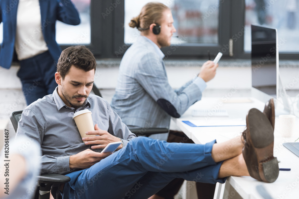 businessman with coffee to go and smartphone in office