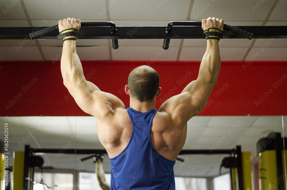 Naklejka premium Back view of strong male athlete with perfect muscles training, doing exercises