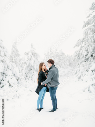 Happy young couple in winter forest. Winter love story.