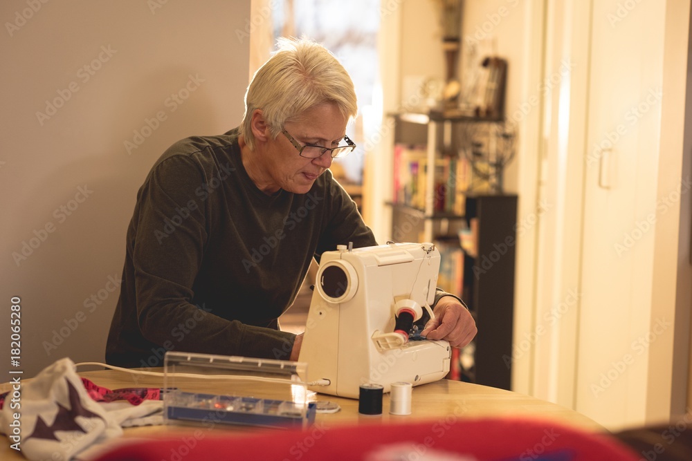 Senior woman using a sewing machine Senior woman using a sewing machine