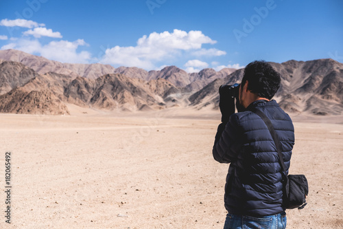Photography A man photographer taking a landscape photo of desert , mountains and blue sky
