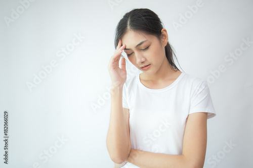 Woman touching her head with hands. Young asian woman feel headache. Isolated on white background. © Bavorndej