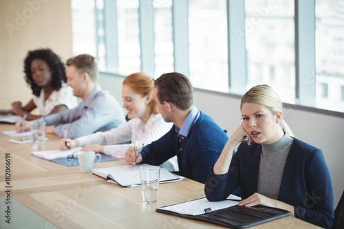 Thoughtful businesswoman sitting with colleagues at desk