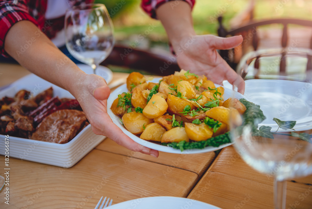 Woman serving roasted potatoes on dining table