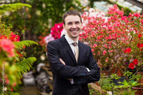 Attractive smiling young men in a business suit in a flower garden. Concept of a successful 