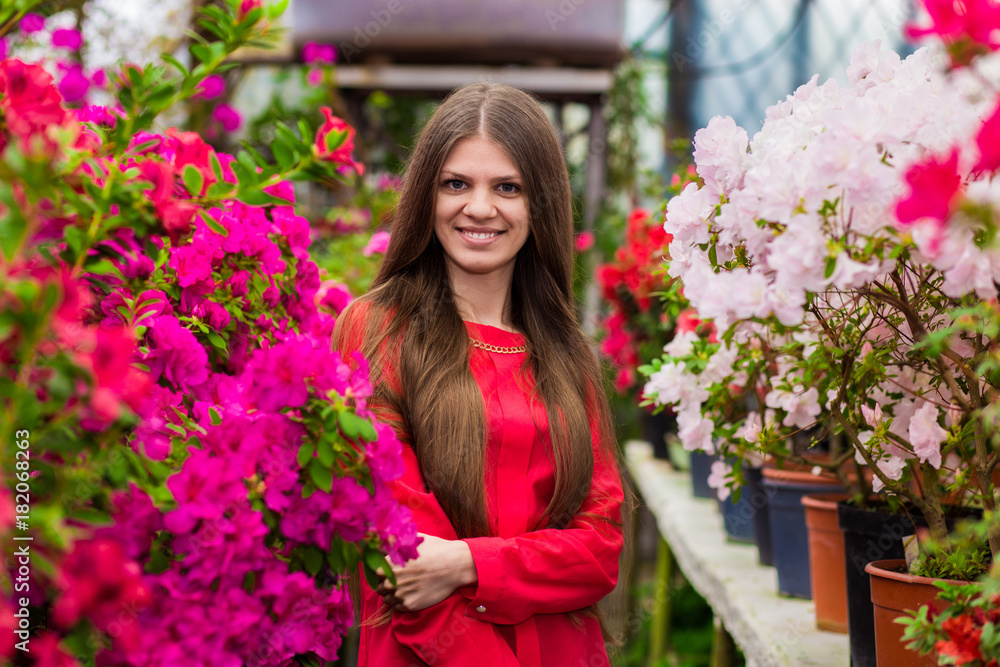 Pretty smiling young women with very long hair in a red blouse in a rose garden Pretty smiling young women with very long hair in a red blouse in a rose garden