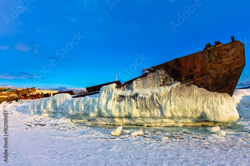 Old rusty ship on ice covered sunset standing on the shore photo