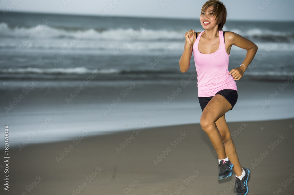young attractive and fit Asian sport runner woman running on beach sea side smiling happy in fitness young attractive and fit Asian sport runner woman running on beach sea side smiling happy in fitness