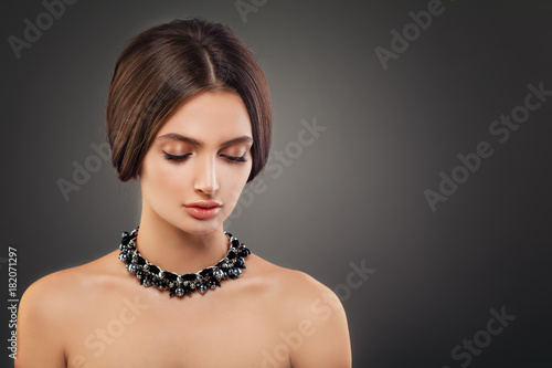 Beautiful Young Woman Fashion Model with Pearls Necklaces and Makeup on Dark Background