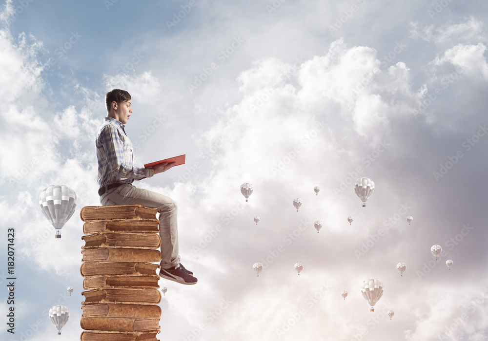 Man student on stack reading book and aerostats flying around Man student on stack reading book and aerostats flying around