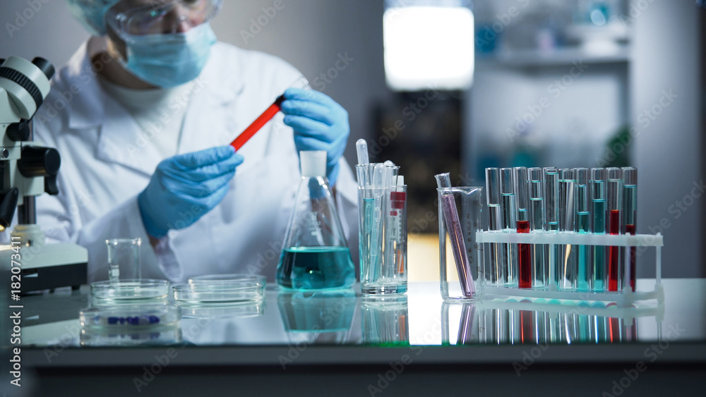 Laboratory assistant examining medical blood sample, looking for sediments Laboratory assistant examining medical blood sample, looking for sediments