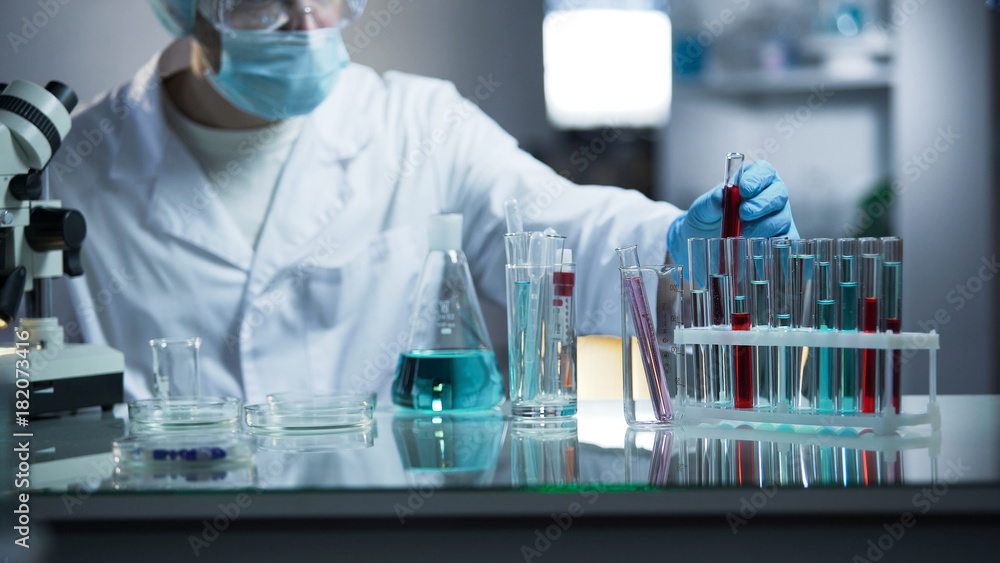 Lab worker putting medical blood sample in place after examining for sediments Lab worker putting medical blood sample in place after examining for sediments