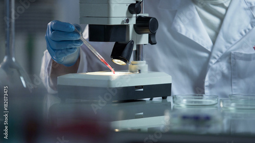 Medical examiner researching blood particles found on victim body to find killer
