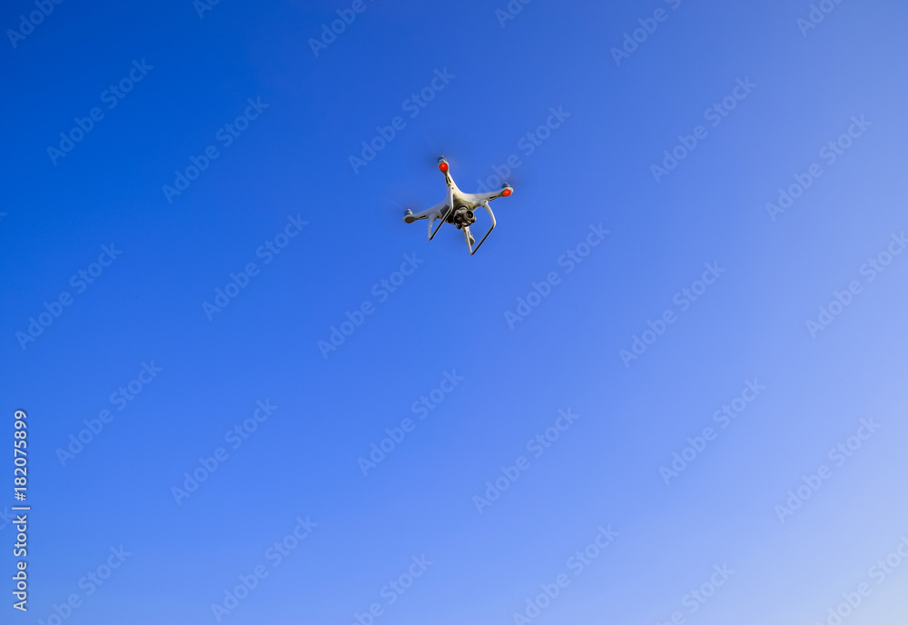The flight of the Copter in the clear blue sky. White drone. The flight of the Copter in the clear blue sky. White drone.