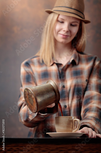 Beautiful woman pours coffee into the cup .
