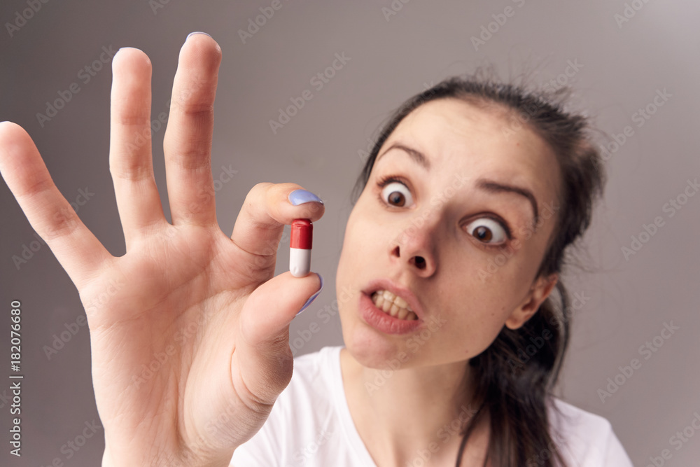 Woman sick, pill in hand on gray background Woman sick, pill in hand on gray background
