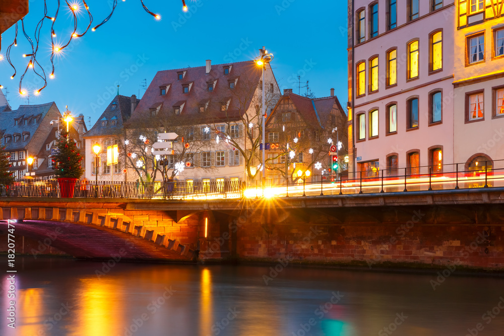 Picturesque Christmas quay with mirror reflections in the river Ile during evening blue hour, Strasbourg, Alsace, France