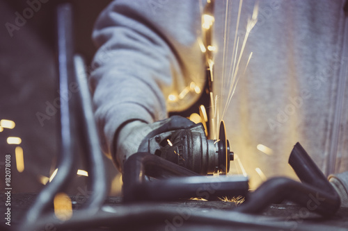 Creative and colored  horizontal image of man working with steel pipe  producing golden sparks on the work surface.