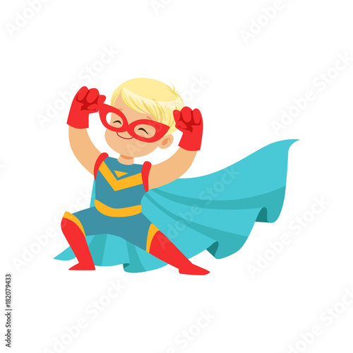 Comic happy kid in superhero costume, red mask and gloves, blue cape developing in the wind, posing and showing muscles.