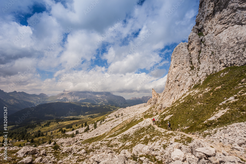 Two trekkers along path with beautiful dolomitic landscape, Valparola Pass, Dolomites, Italy