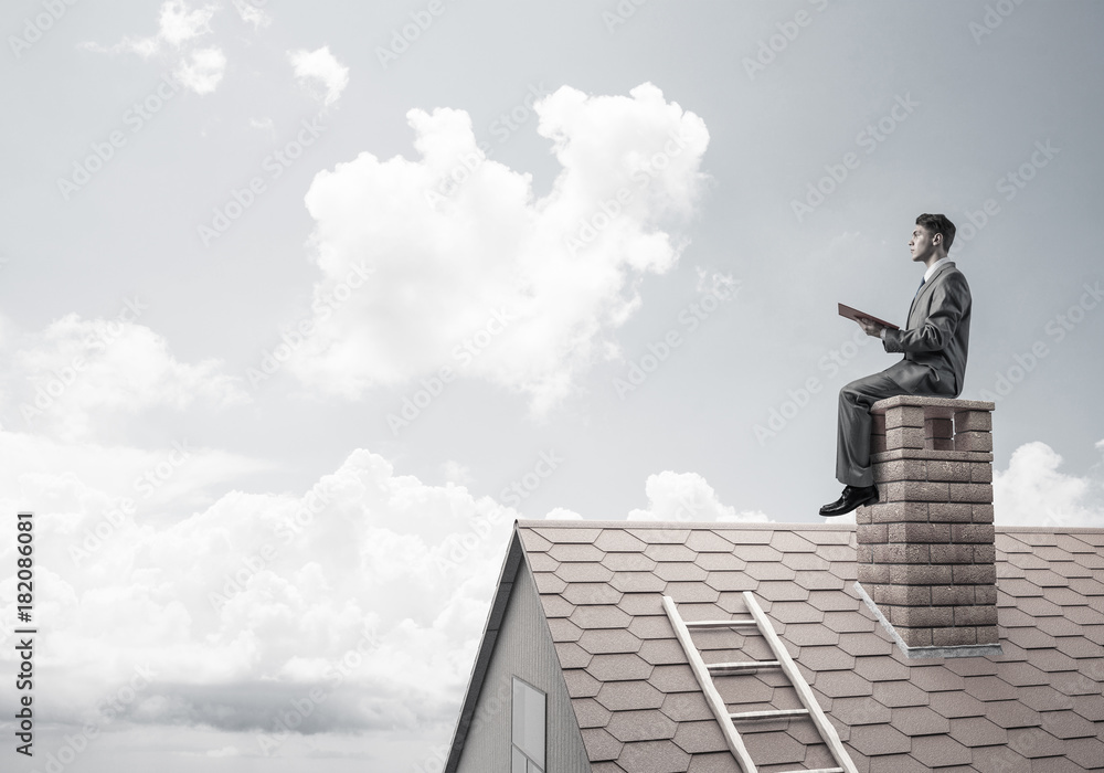 Student guy in suit on brick house roof reading book Student guy in suit on brick house roof reading book