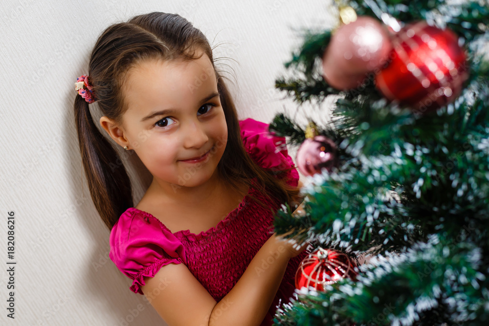 An adorable preschooler preparing to place balls on her tiny Christmas tree. On a white background. An adorable preschooler preparing to place balls on her tiny Christmas tree. On a white background.