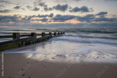 sunrise over groynes in bay