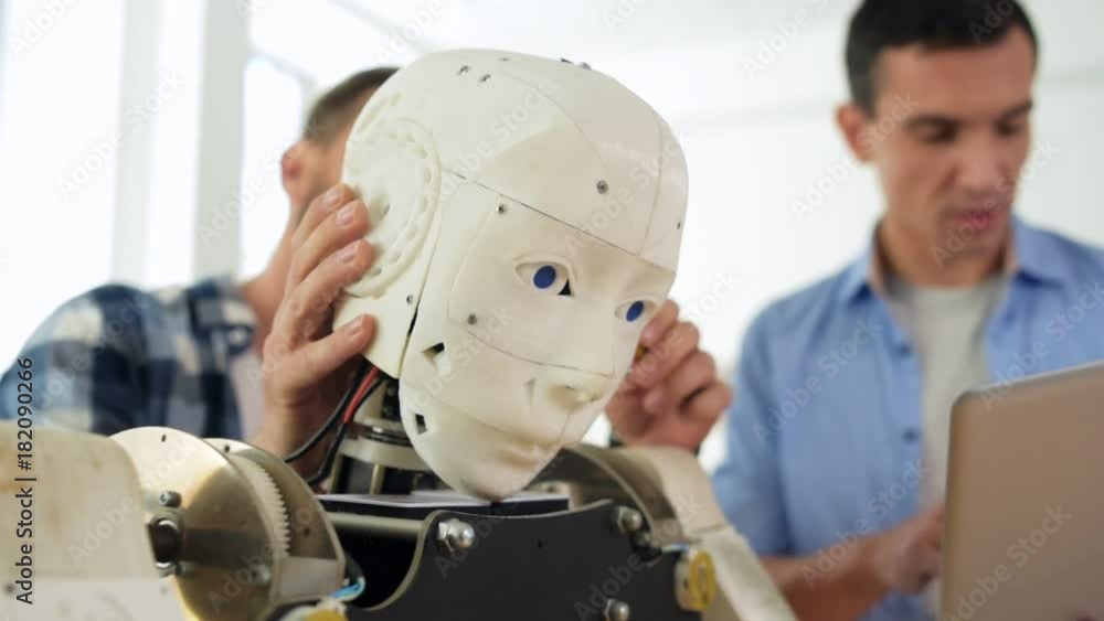 Diligent worker. Close up of robots head and skilled constructor repairing specific parts of the mockup Diligent worker. Close up of robots head and skilled constructor repairing specific parts of the mockup