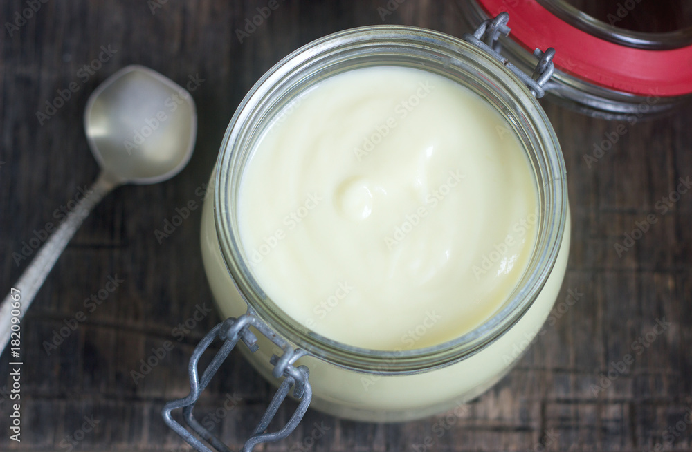 Custard vanilla cream in a glass jar on a wooden background. Custard vanilla cream in a glass jar on a wooden background.
