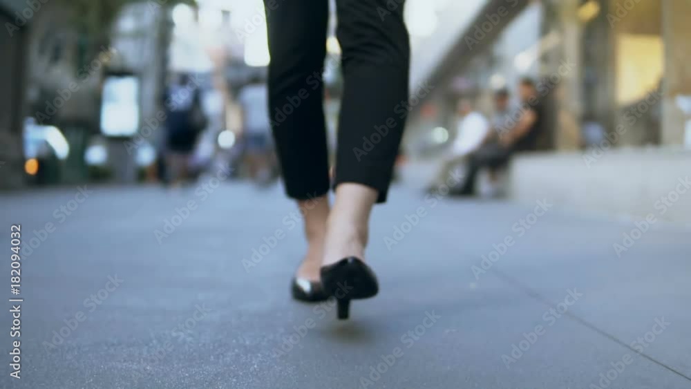 Close-up view of female feet walking through the downtown. Businesswoman wearing shoes with heels. Slow motion. Close-up view of female feet walking through the downtown. Businesswoman wearing shoes with heels. Slow motion.