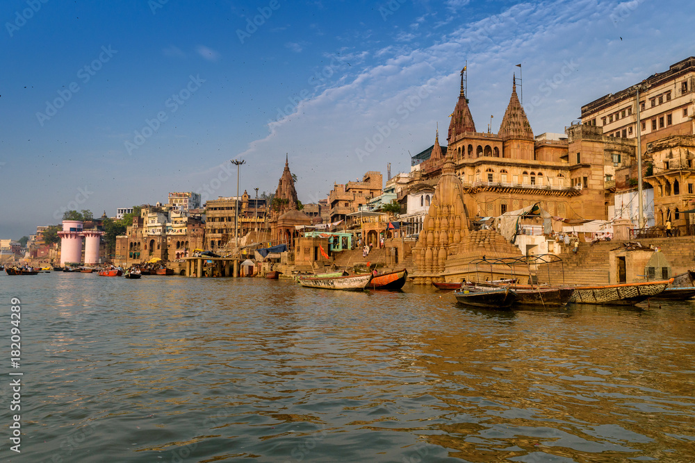 Fototapeta premium A view from River Ganges of Old Historical Varanasi city with weathered buildings at the time of Sunrise