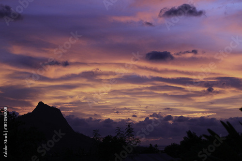A Mountain Peak and Treeline is Silhouetted in Sunset by a brilliant purple sky. Taken in Wae Rebo, Indonesia. photo
