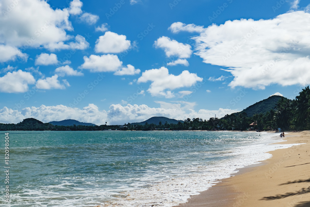 Beautiful seascape with sea waves and sandy beach under cloudy blue sky, Maenam beach, Koh Samui, Thailand.
