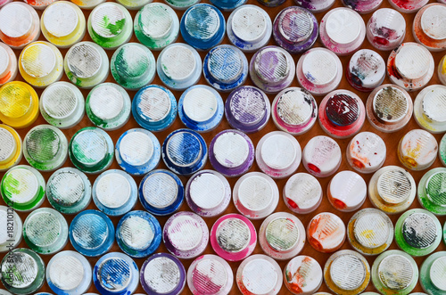 A pattern from a many nozzles from a paint sprayer for drawing graffiti, smeared into different colors. The plastic caps are arranged in many rows forming the color of the rainbow