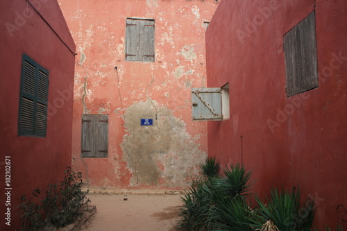grey windows and pink walls of a street of goree island in senegal