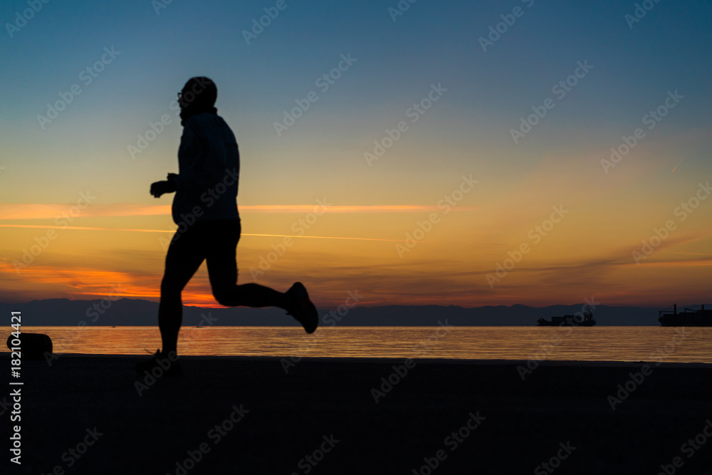 Sihouette of Man Wearing Glasses, Running by the Sea, against beautiful after sunset color tones