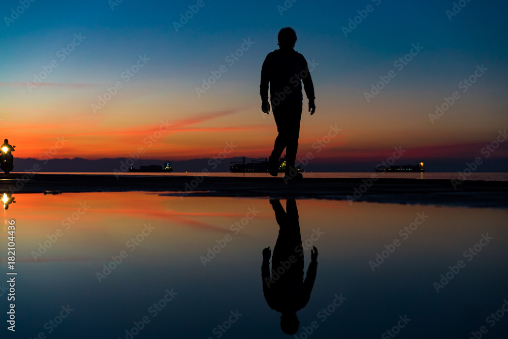 Sihouette of Man Walking by the Sea, against beautiful after sunset color tones