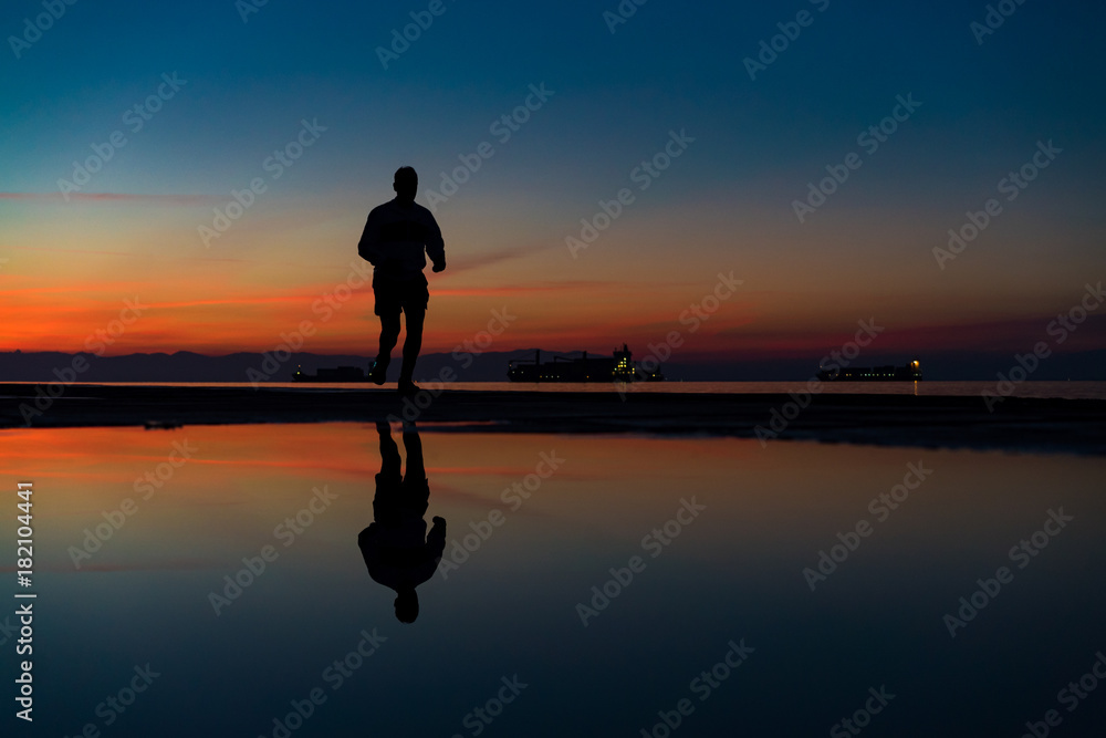 Sihouette of Man Running by the Sea, against beautiful after sunset color tones