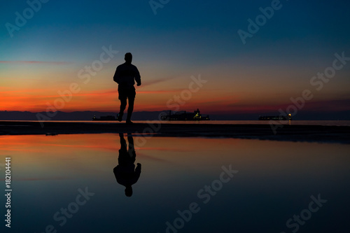 Sihouette of Man Running by the Sea, against beautiful after sunset color tones