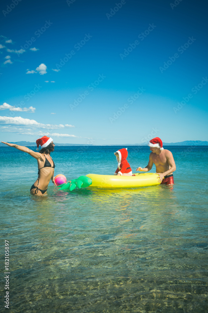 christmas family in santa hat at beach water with mattress
