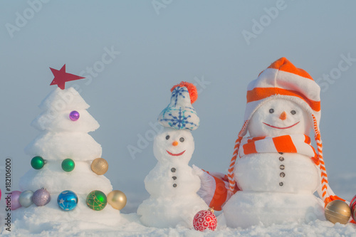 Snowmen with smiley faces in hats on winter day