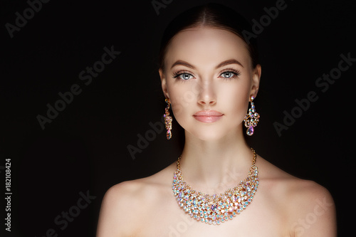 Model in set of jewellery. Luxury girl in shine jewelry from precious stones, diamonds. Beautiful woman in a necklace, earrings and big ring. Beauty and accessories.