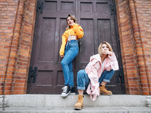 Two fashion Chinese girls making poses in front of a retro style wooden door in Shanghai bund. photo