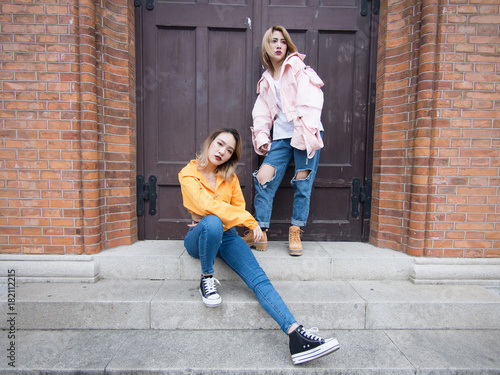 Two fashion Chinese girls makng poses in front of a retro style wooden door in Shanghai bund. photo