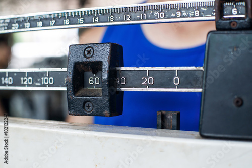 Sport man weighing himself on balance weight scale at the gym