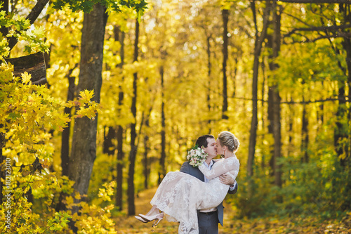 The bride and groom on the background of the brightly lit Golden autumn © alenazamotaeva