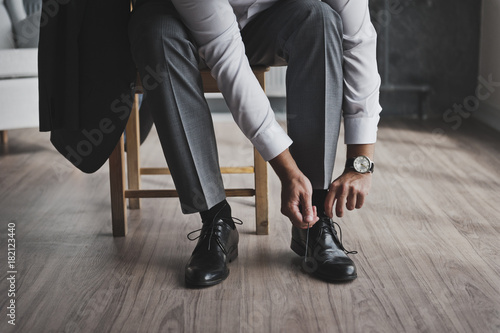 A man in a business suit ties the laces 335.