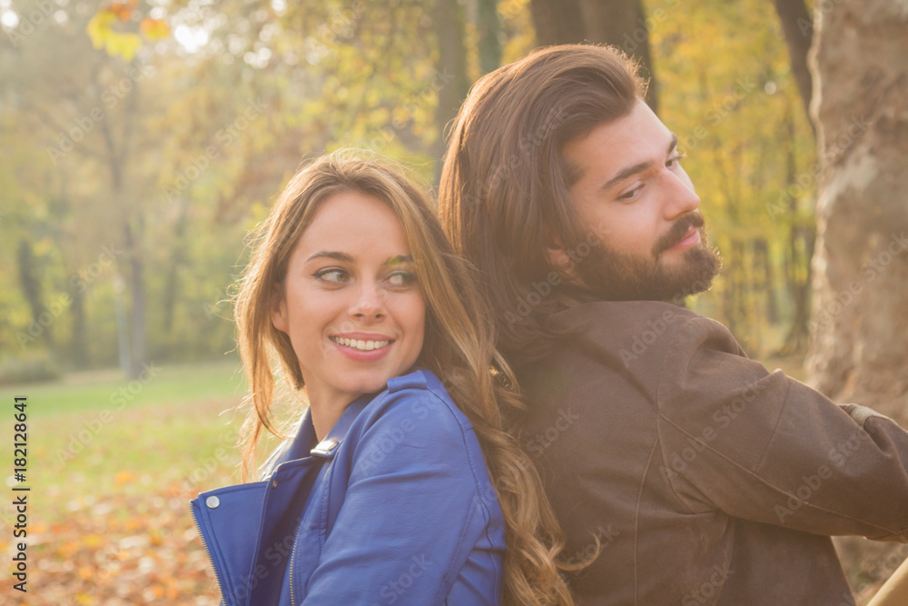 Cute couple sitting on a bench in park filled with autumn colors. Cute couple sitting on a bench in park filled with autumn colors.
